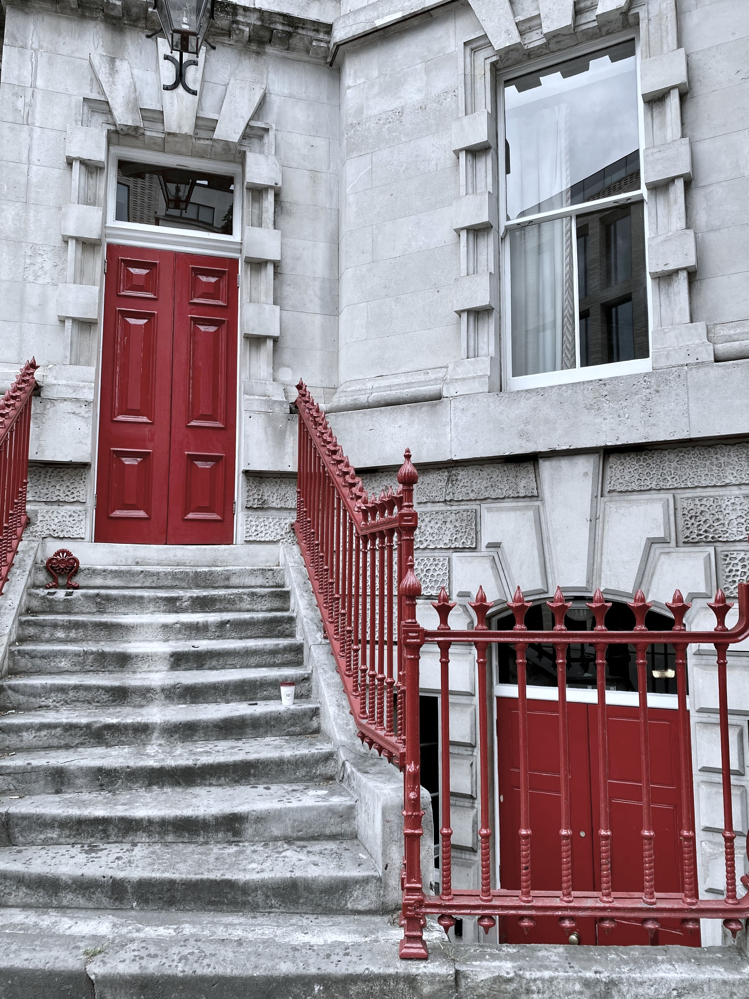 Rote Haustür über einer Treppe, darunter eine zweite Tür hinter Gittern (Foto: CrowN / Unsplash)